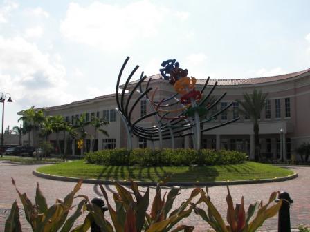 Abstract sculpture in grassy area outside building with brick paving around